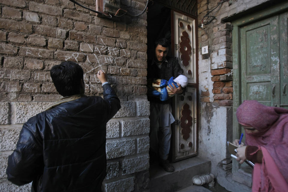 In this Feb. 9, 2014 photo, a Pakistani health worker, marks a sign on a wall to let others know that the home has been visited by health workers, who have given a polio vaccine to a child living there, in Peshawar, Pakistan. Pakistan’s beleaguered battle to eradicate polio is threatening a global, multi-billion dollar campaign to wipe out the disease worldwide. Because of Pakistan, the virus is spreading to countries that were previously polio free, say U.N. officials. “The largest poliovirus reservoir of the world,” is in Peshawar, the capital of Pakistan’s northwest Khyber Pukhtunkhwa province, which borders Afghanistan, according to the World Health Organization. (AP Photo/Mohammad Sajjad)