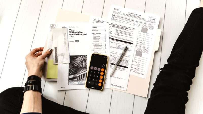 A person sitting on the floor with their tax documents laid out in front of them.