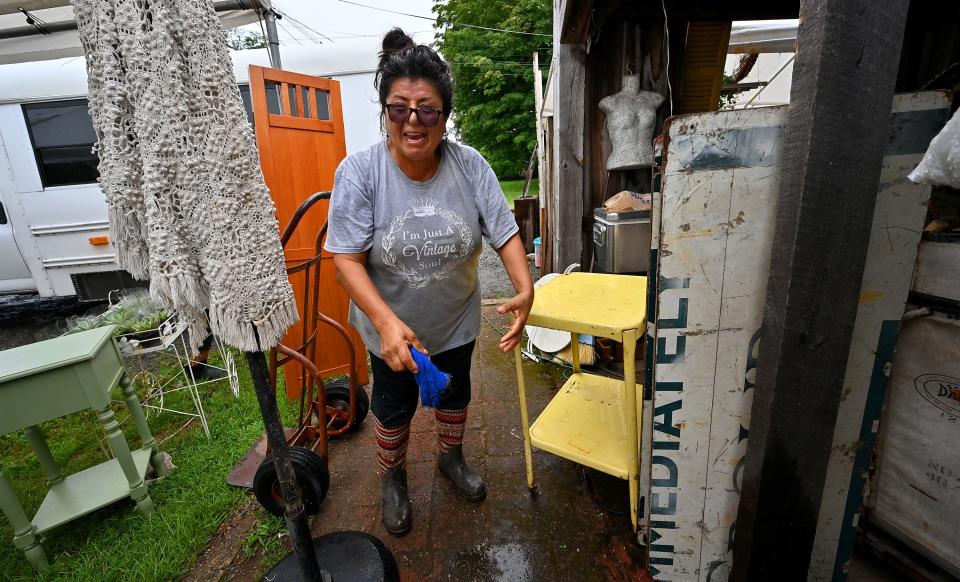 Luz Punto of Tampa, Florida, wrings out a wet rag while wiping wet furniture after the heavy rain came through during set up day at Brimfield Flea Market Monday.