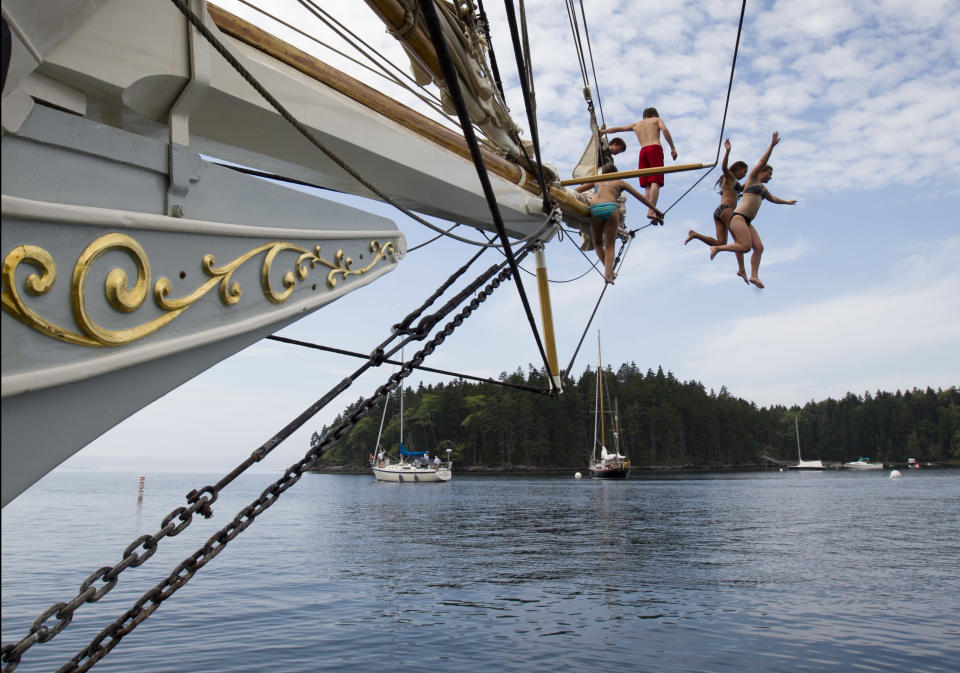 In this photo made Friday, August 3, 2012, Olivia Trankina of Marietta, Ga., and Liz Archibald of Clarks Summit, Penn., leap from the bowsprit of the schooner Mary Day in Bucks Harbor in South Brooksville, Maine. The 90-foot Mary Day, which is celebrating its 50th season, is the first schooner in the Maine windjammer fleet to be built specifically to accommodate passengers. Its sleeping cabins are heated and have nine feet of headroom. (AP Photo/Robert F. Bukaty)