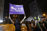 A demonstrator holds up a sign reading "Back away slowly" to encourage other demonstrators to leave, near the Chinese Liaison Office in Hong Kong, Sunday, Aug. 18, 2019. Protesters turned Hong Kong streets into rivers of umbrellas Sunday as they marched through heavy rain from a packed park and filled a major road in the Chinese territory, where mass pro-democracy demonstrations have become a regular weekend activity this summer. (AP Photo/Vincent Thian)