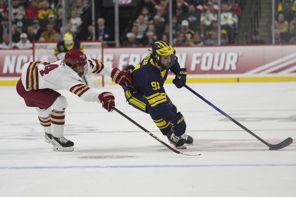 Boston College forward Gabe Perreault, left, and Michigan forward Frank Nazar III (91) vie for the puck during the first period of a semifinal at the men's Frozen Four NCAA college hockey tournament Thursday, April 11, 2024, in St. Paul, Minn. (AP Photo/Abbie Parr)