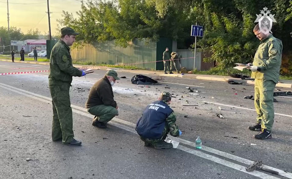 This handout photo taken from video released by Investigative Committee of Russia on Sunday, purports to show investigators working on the site littered with debris from the bombed car driven by Daria Dugina outside Moscow. 