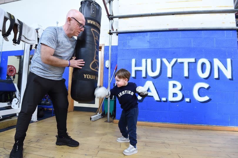 Boxing Coach Andy Robinson,with his son Teddy aged 3,on the punchbag at Huyton A.B.C.