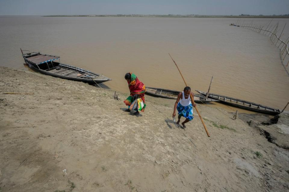 Monuwara Begum and husband Yaad Ali disembark from a boat and walk to a polling station in Assam (AP)