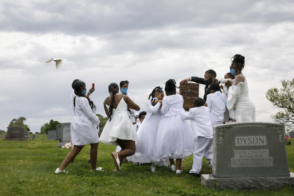 Grandchildren of Joanne Paylor, of southwest Washington, react to doves as they are released by Compassion and Serenity Funeral Home Administrator Dani Skinner, during the interment ceremony for Paylor at Lincoln Memorial Cemetery in Suitland-Silver Hill, Md., Sunday, May 3, 2020. The family delayed Paylor's funeral for almost two months hoping the social distancing rules would be lifted. Despite not having died from coronavirus, almost every aspect of her funeral has been impacted by the pandemic. (AP Photo/Jacquelyn Martin)