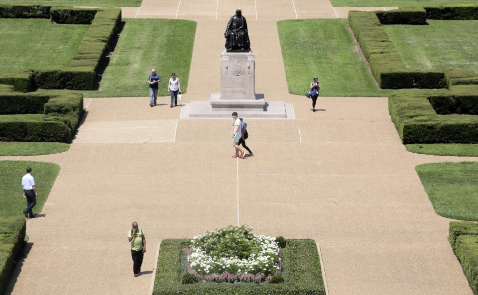 In this Friday, June 7, 2019, photo, people walk by the statue of Rice University founder William Marsh Rice on the campus, in Houston. Rice University started a new task force, which will explore its history and connections to slavery, segregation and racial injustice. (Elizabeth Conley/Houston Chronicle via AP)