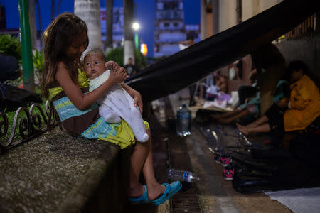 Fanny Jackeline, una niña de siete años de Honduras, sostiene a su hermana de dos meses de edad, Montserrat, en medio de una caravana de miles de migrantes de América Central que descansan mientras viajan a Estados Unidos, en el centro de la ciudad de Tapachula, México, 21 de octubre de 2018.. REUTERS/Adrees Latif