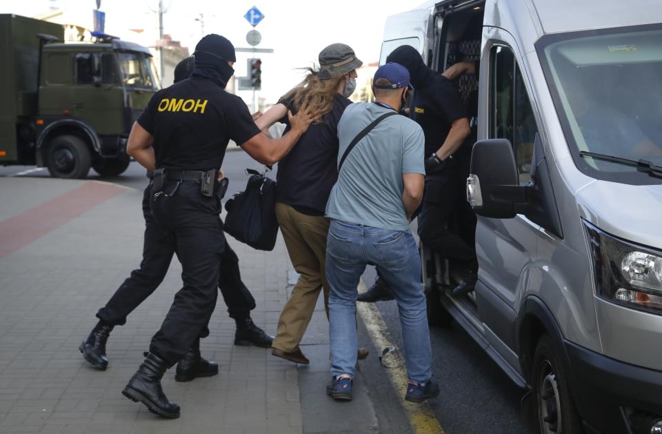 Belarusian police officers detain a man in Minsk, Belarus, Saturday, Aug. 8, 2020. On Saturday evening, police arrested at least 10 people as hundreds of opposition supporters drove through the center of the capital waving flags and brandishing clenched-fist victory signs from the vehicles' windows. The presidential election in Belarus is scheduled for August 9, 2020. (AP Photo/Sergei Grits)