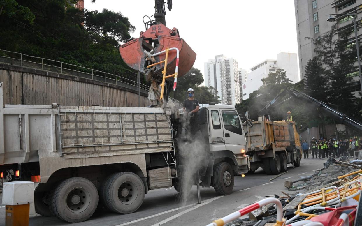 A worker removes debris left by pro-democracy protesters near the Chinese University of Hong Kong (CUHK) on November 16, 2019. - AFP