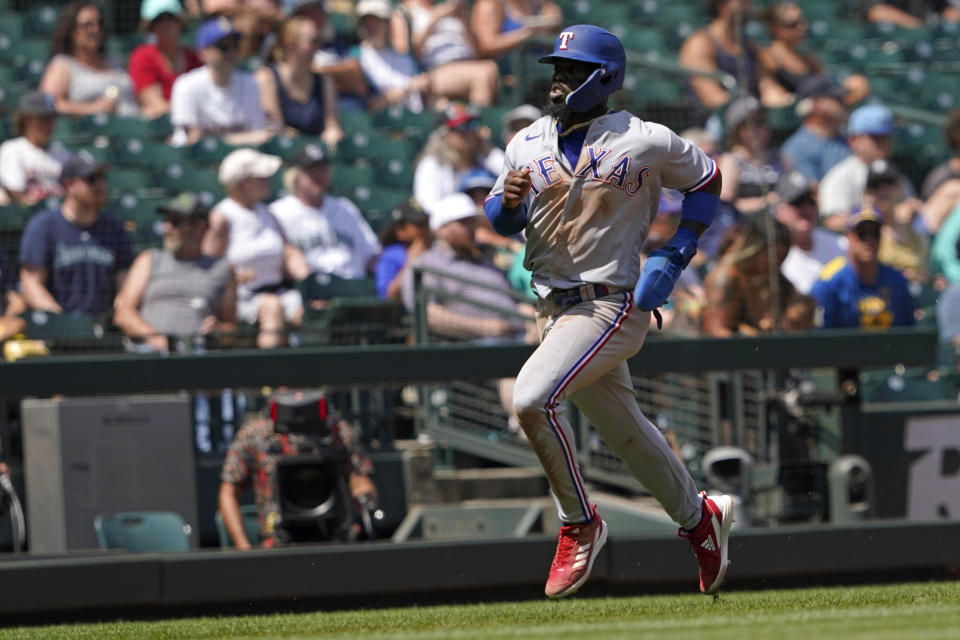 Texas Rangers' Adolis Garcia heads home to score on an RBI-double hit by Charlie Culberson during the fifth inning of a baseball game against the Seattle Mariners, Wednesday, July 27, 2022, in Seattle. (AP Photo/Ted S. Warren)