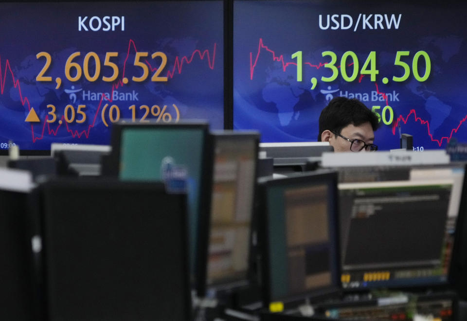 A currency trader watches monitors in front of screens showing the Korea Composite Stock Price Index (KOSPI), top left, and the foreign exchange rate between U.S. dollar and South Korean won at the foreign exchange dealing room of the KEB Hana Bank headquarters in Seoul, South Korea, Tuesday, July 4, 2023. (AP Photo/Ahn Young-joon)