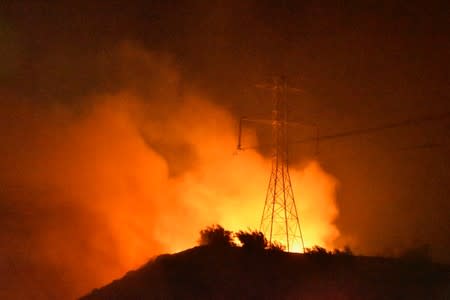 A wind-driven wildfire burns near power lines in Sylmar, California