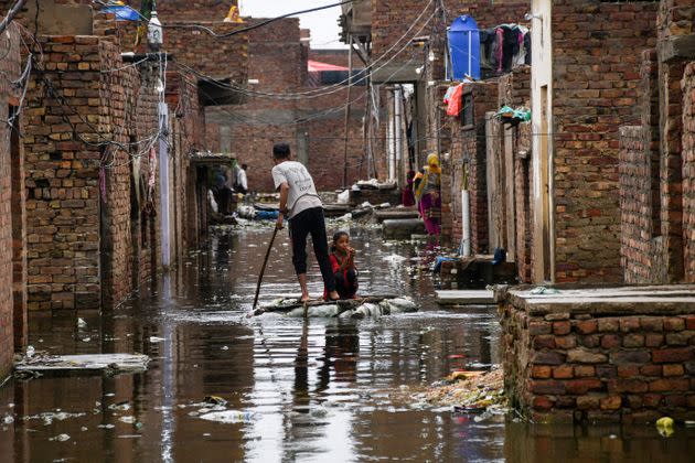 A man and a girl use a makeshift raft as they cross a flooded street, following rains during the monsoon season in Hyderabad, Pakistan, on Aug. 24, 2022. (Photo: STRINGER/REUTERS)