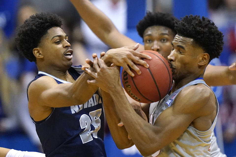 Nevada's Grant Sherfield (25) and Kansas' Ochai Agbaji battle for a rebound during the first half of an NCAA college basketball game Wednesday, Dec. 29, 2021, in Lawrence, Kan. (AP Photo/Charlie Riedel)