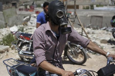 FILE PHOTO: A man drives his motorcycle as he wears a gas masks after what activists said was a chlorine gas attack on Kansafra village at Idlib countryside, Syria May 7, 2015. REUTERS/Abed Kontar