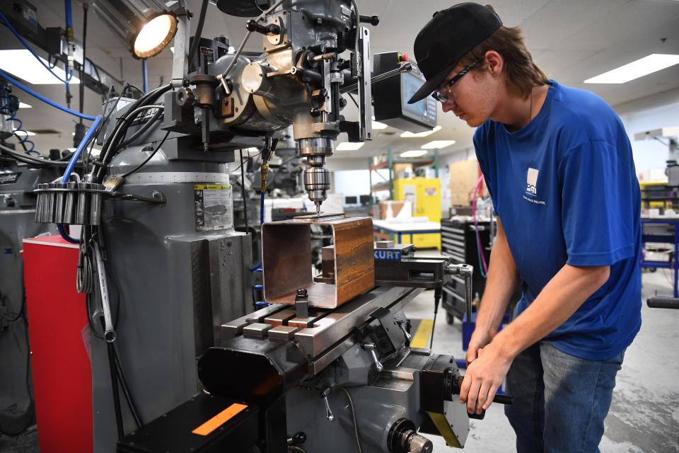 Andrew Clark, a first-year apprentice tool and die maker at PGT Innovations in Venice, adjusts a vertical milling machine.