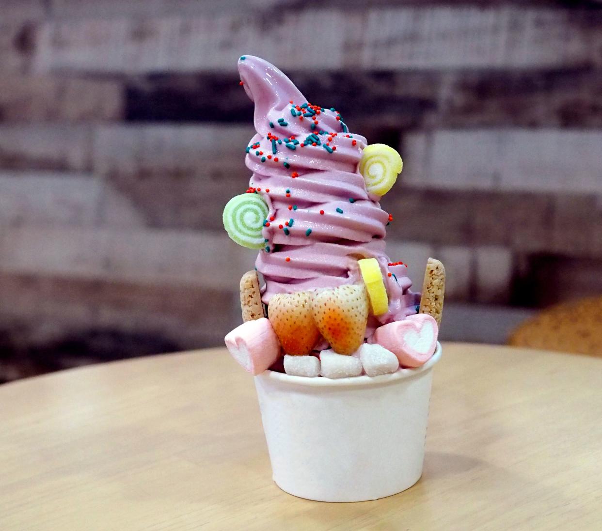 Closeup of organic frozen yogurt Ice cream served in a disposable cup takeaway decorated with candies and fresh strawberry, Healthy eating concept, selective focus.