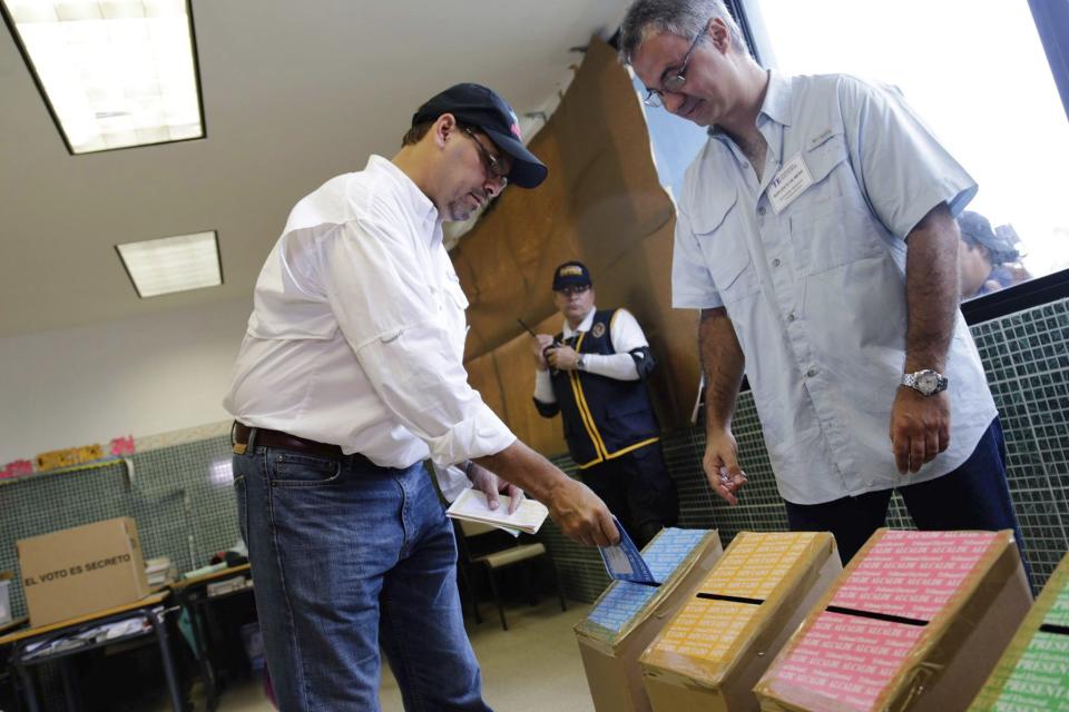 Jose Domingo Arias, left, presidential candidate for the Democratic Change Party, casts his ballots at a polling station in Panama City, Sunday, May 4, 2014. Panamanians are choosing President Ricardo Martinelli's successor in a three-way dogfight marked more by ugly personality clashes than any deep disagreements over the way forward for Latin America's standout economy. (AP Photo/Tito Herrera)
