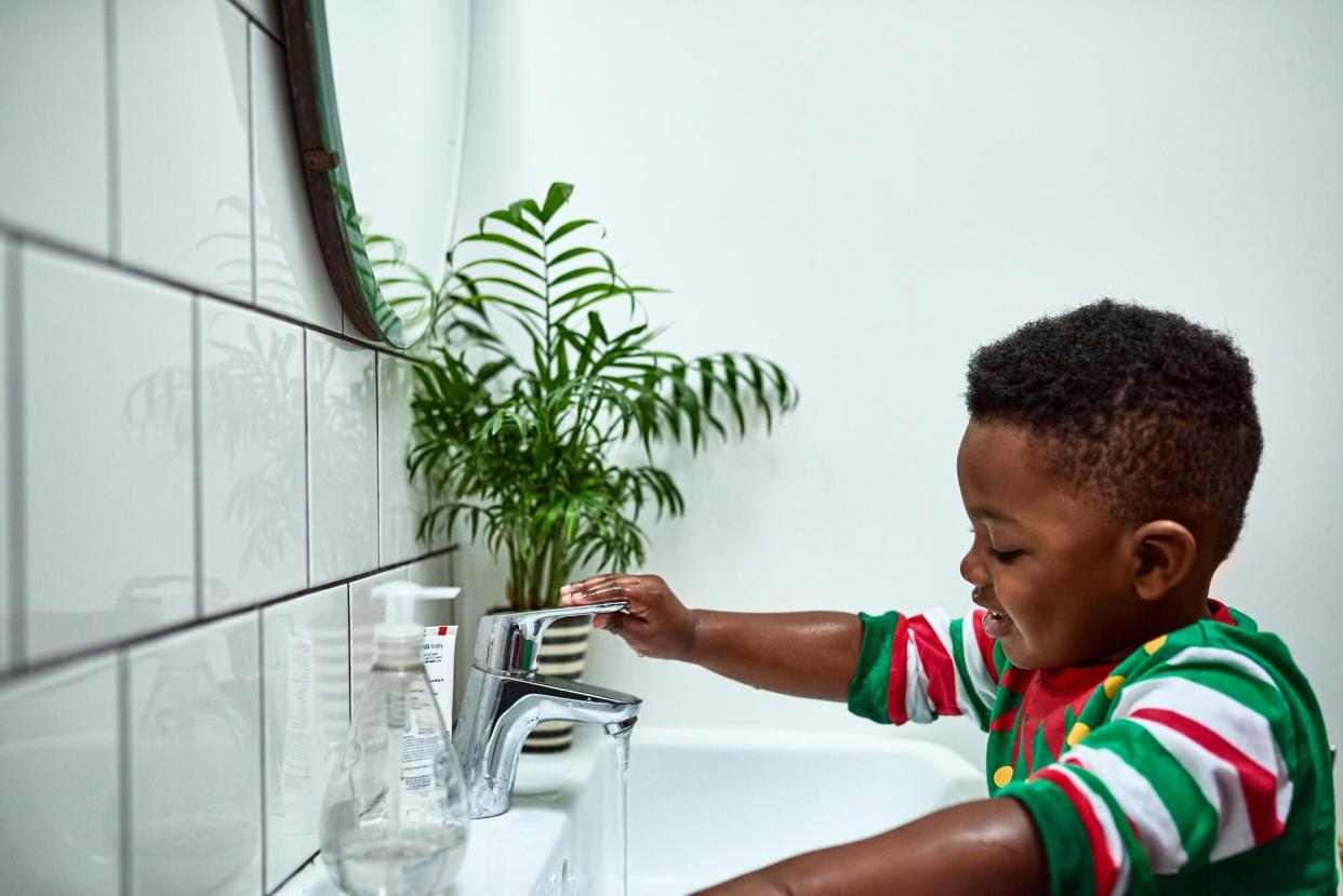 Toddler washing his hands at a sink