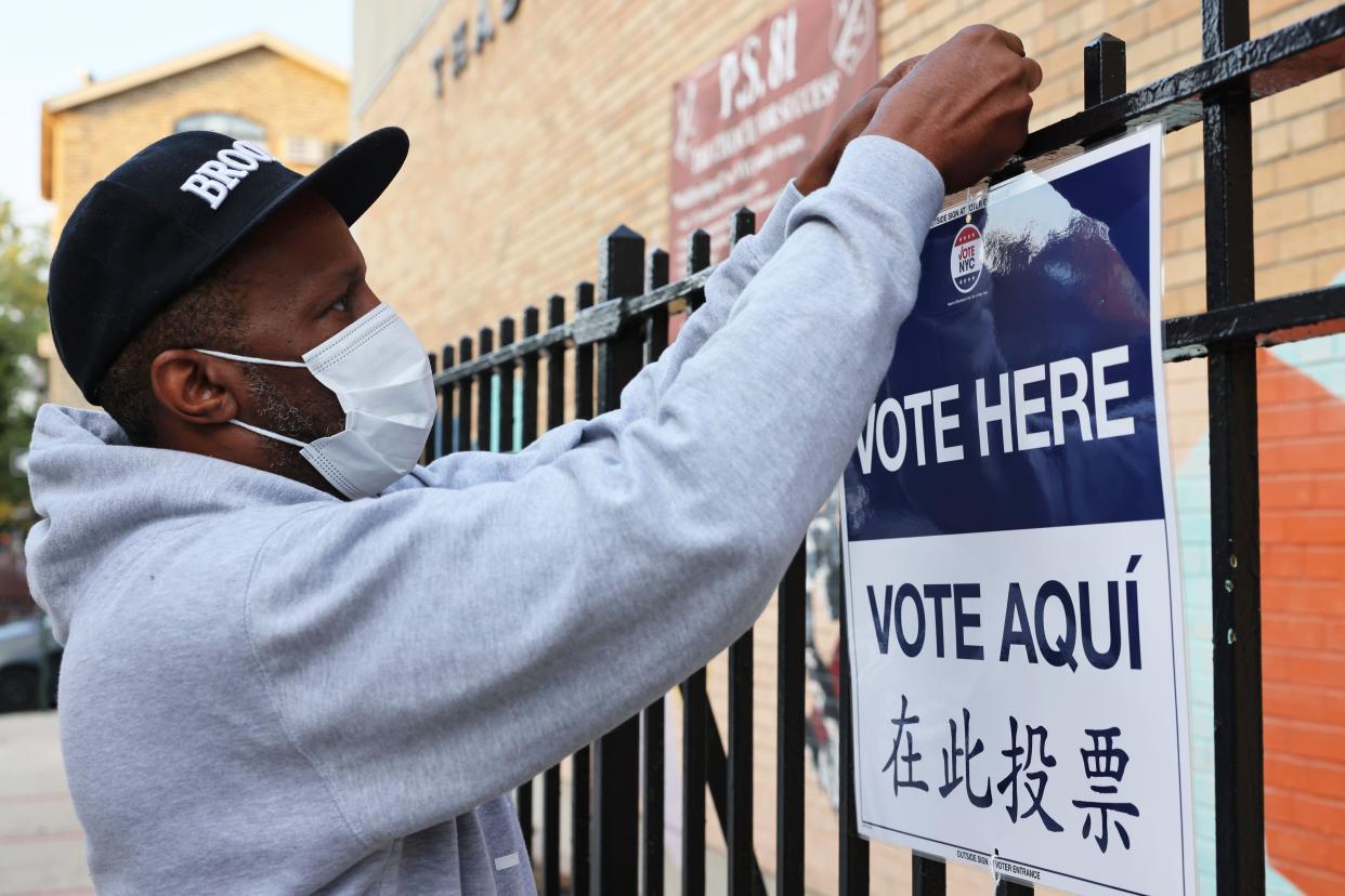 A poll worker hangs up a voting sign during the Primary Election Day at P.S. 81 on June 22, 2021, in the Bedford-Stuyvesant neighborhood of Brooklyn. This is the first year in the city for ranked-choice voting, which allows voters to rank their top five candidates.