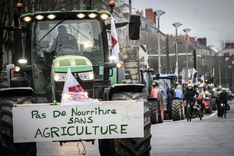 Un agricultor conduce su tractor con un cartel que dice 