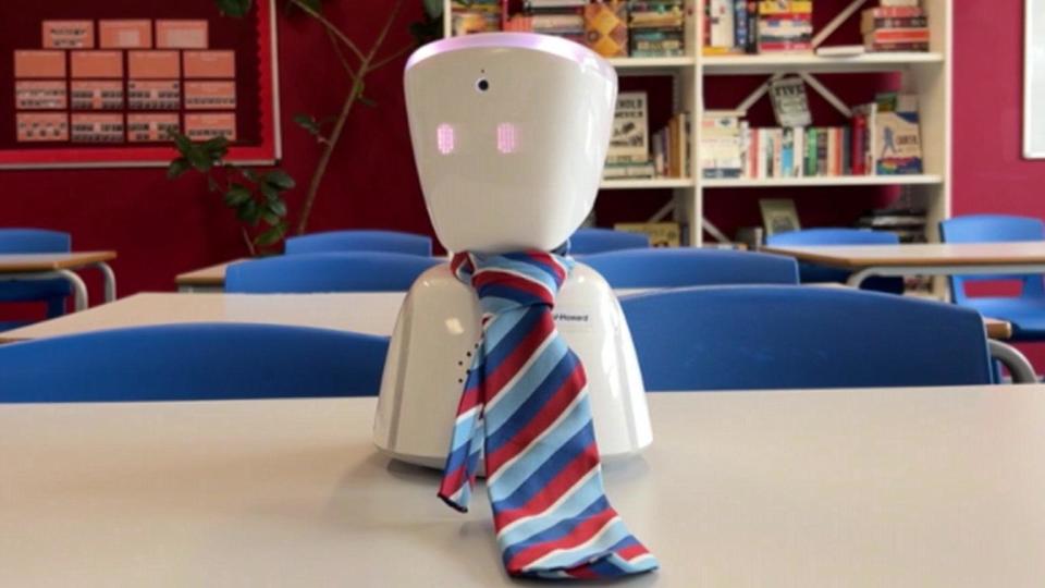 Image of AV Howard, a small white tabletop robot wearing a red and blue striped tie