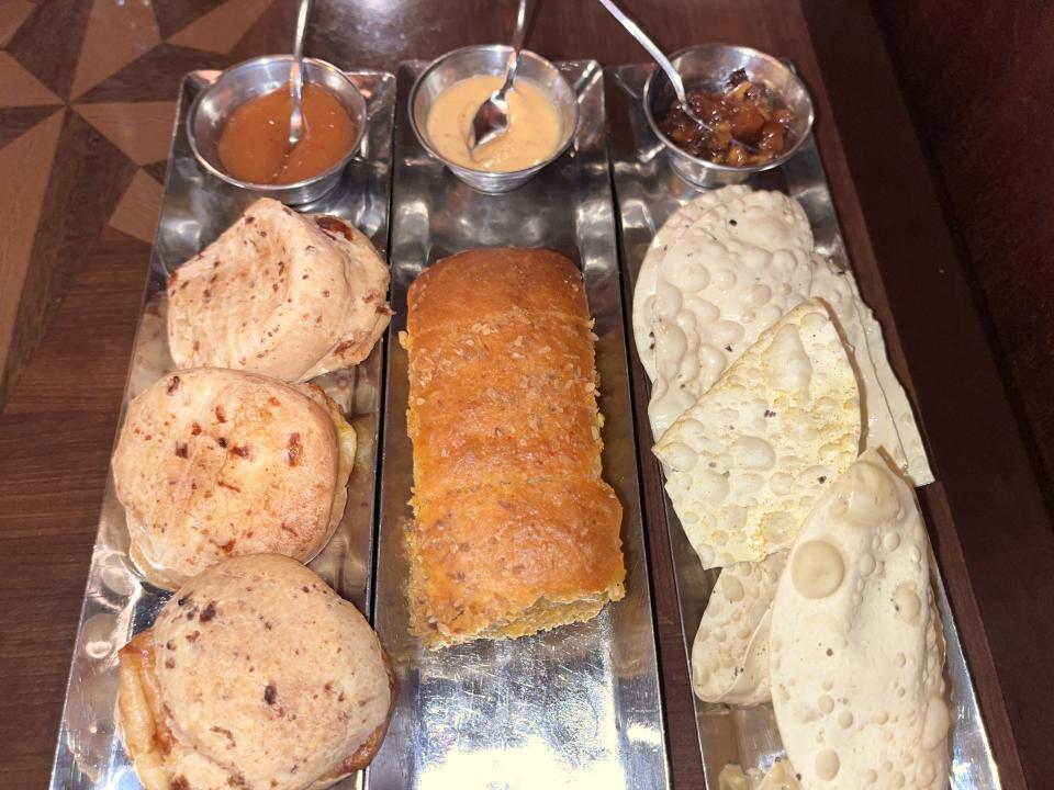 Three types of bread and sauces lined up on trays.