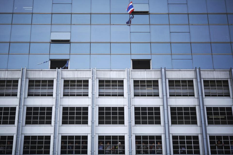 People watch and a supporter waves a flag as anti-government protesters march through Bangkok's financial district January 21, 2014. Some Thai rice farmers have threatened to switch sides and join protesters trying to topple the government if they do not get paid for their crop, a worrying development for Prime Minister Yingluck Shinawatra whose support is based on the rural vote. REUTERS/Damir Sagolj (THAILAND - Tags: POLITICS AGRICULTURE BUSINESS CIVIL UNREST)