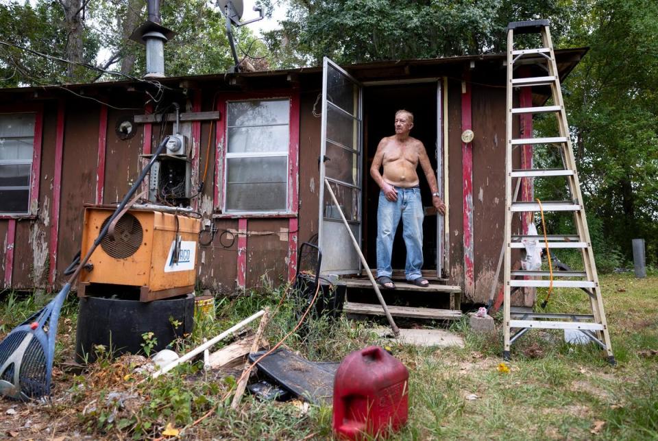 Full-time Sam Houston Lakes Estates resident Kenneth Brister stands in the doorway of his home on the riverfront of the Trinity River on August 22, 2023.