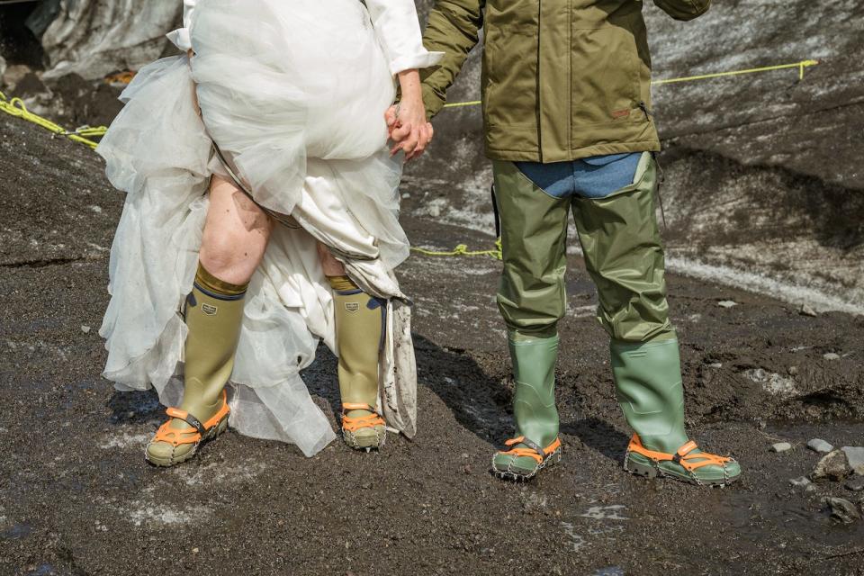 A bride and groom wearing waders and rain boots.