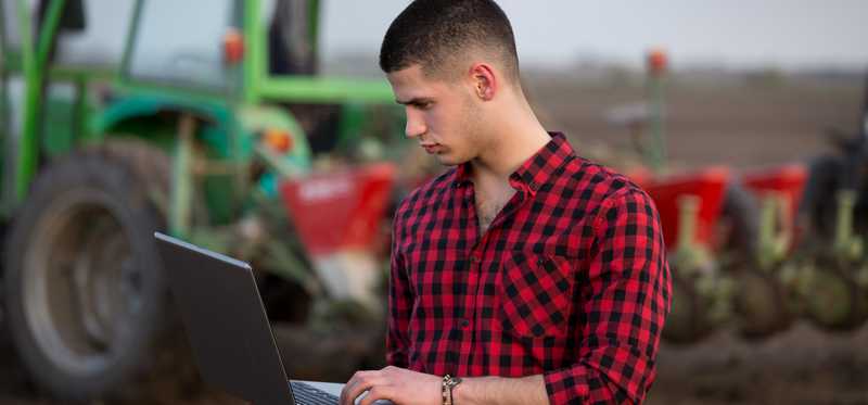 A farmer checks his crops on a laptop.