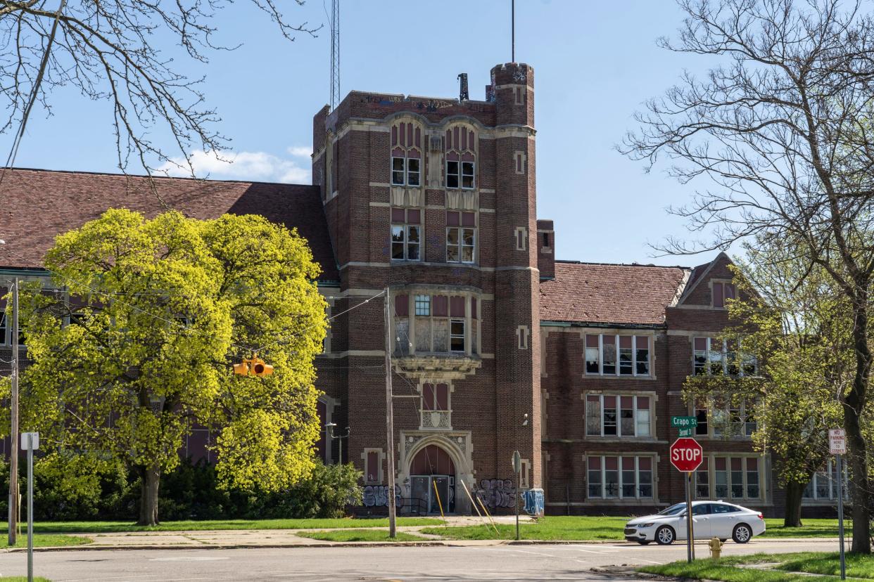 A car drives past the abandoned Flint Central High School, which sits in a neighborhood with broken windows and next to the abandoned Whittier Classical Academy in Flint on Thursday, April 19, 2024.