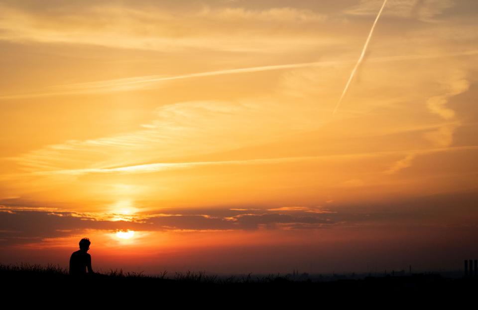 A man sitting at Drachenberg mountain watches the sun rising over Berlin on June 26, 2019). - As Europe sizzled at the start of a heatwave tipped to break records, meteorologists blamed a blast of torrid air from the Sahara for the unusually early summer heatwave, which could send thermometers above 40 degrees Celsius (104 Fahrenheit) in some places in Europe on Thursday and Friday. (Photo by Kay Nietfeld / dpa / AFP) / Germany OUT        (Photo credit should read KAY NIETFELD/AFP/Getty Images)