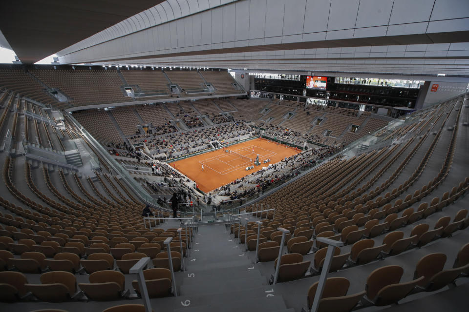 FILE - Rows of empty seats are seen at centre court at the Roland Garros stadium in Paris Sunday, Oct. 11, 2020, as Serbia's Novak Djokovic and Spain's Rafael Nadal warm up for the final match of the French Open tennis tournament. All COVID-19 related restrictions have been lifted and crowds are expected to fill the stadium. (AP Photo/Alessandra Tarantino, FILE)