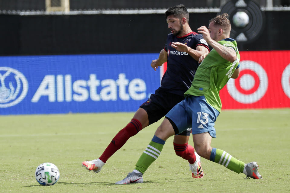 Chicago Fire defender Mauricio Pineda, left, and Seattle Sounders forward Jordan Morris (13) fight for position on the ball during the second half of an MLS soccer match, Tuesday, July 14, 2020, in Kissimmee, Fla. (AP Photo/John Raoux)