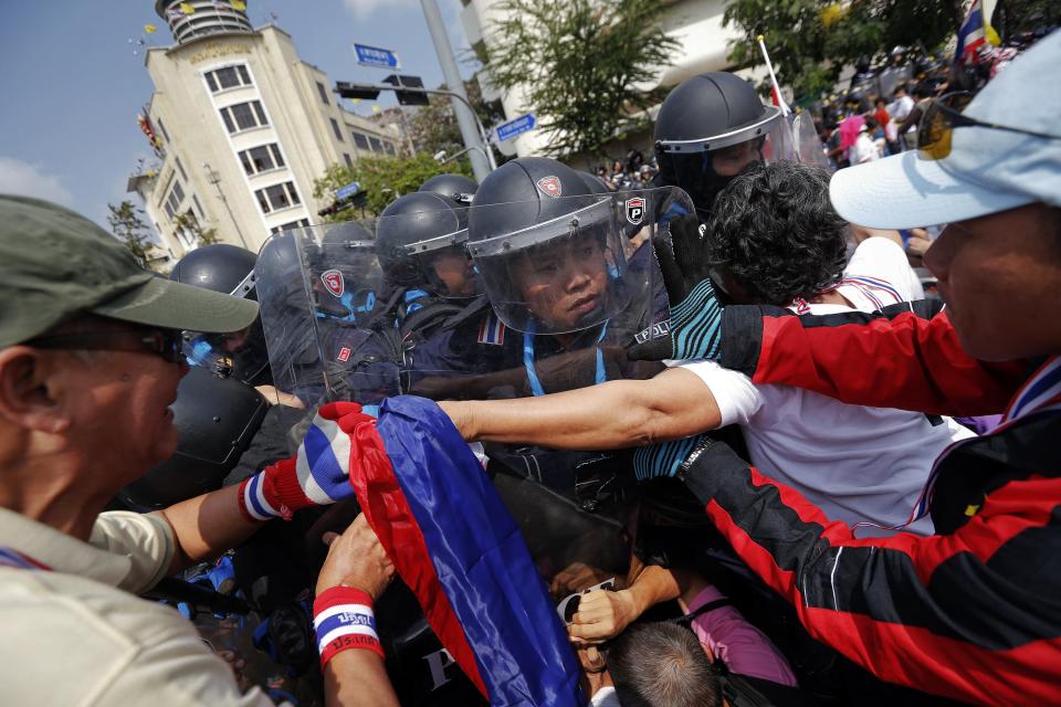 Policemen charge against anti-government protesters at one of their barricades near the Government House in Bangkok