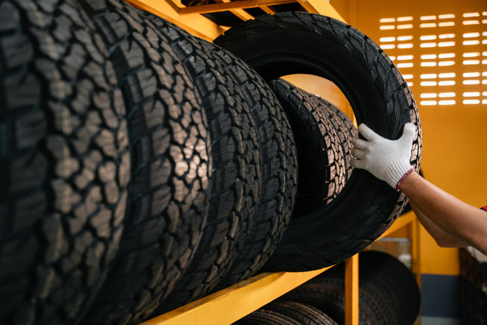 Person's hand selecting a tire from a rack of various tires