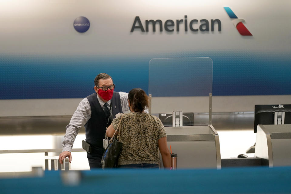 American Airlines ticket agent Henry Gemdron, left, works with a customer at Miami International Airport during the coronavirus pandemic, Wednesday, Sept. 30, 2020, in Miami. The airline industry has been decimated by the pandemic. The Payroll Support Program given to the airlines as part of the CARES Act runs out Thursday. (AP Photo/Lynne Sladky)