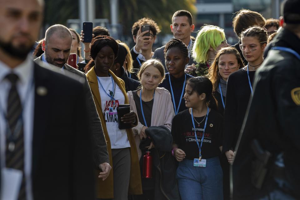 Climate activist Greta Thunberg, center and left, walks at the COP25 climate talks summit in Madrid, Friday Dec. 6, 2019. Thunberg arrived in Madrid Friday to join thousands of other young people in a march to demand world leaders take real action against climate change. (AP Photo/Bernat Armangue)