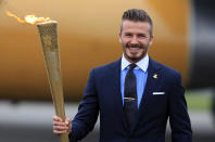 David Beckham holds the Olympic Flame as it arrives at RNAS Culdrose near Helston on May 18, 2012 in Cornwall, England. The Olympic Flame arrived in the UK after it was handed over at a ceremony yesterday in Athens. A British delegation including David Beckham, flew back with the flame from Greece where they attended a ceremony welcoming the flame, before it is taken on a 70-day relay involving 8,000 torchbearers covering 8,000 miles. (Photo by Matt Cardy/Getty Images)