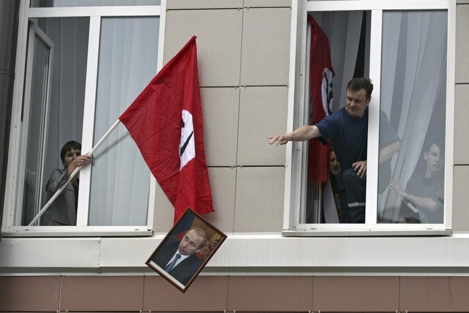 FILE - National Bolshevik party members storm the Health Ministry and throw out a portrait of President Vladimir Putin, as they protest legislation to turn social benefits into cash payments in downtown Moscow, Russia, on Monday, Aug. 2, 2004. (AP Photo/Sergey Ponomarev, File)