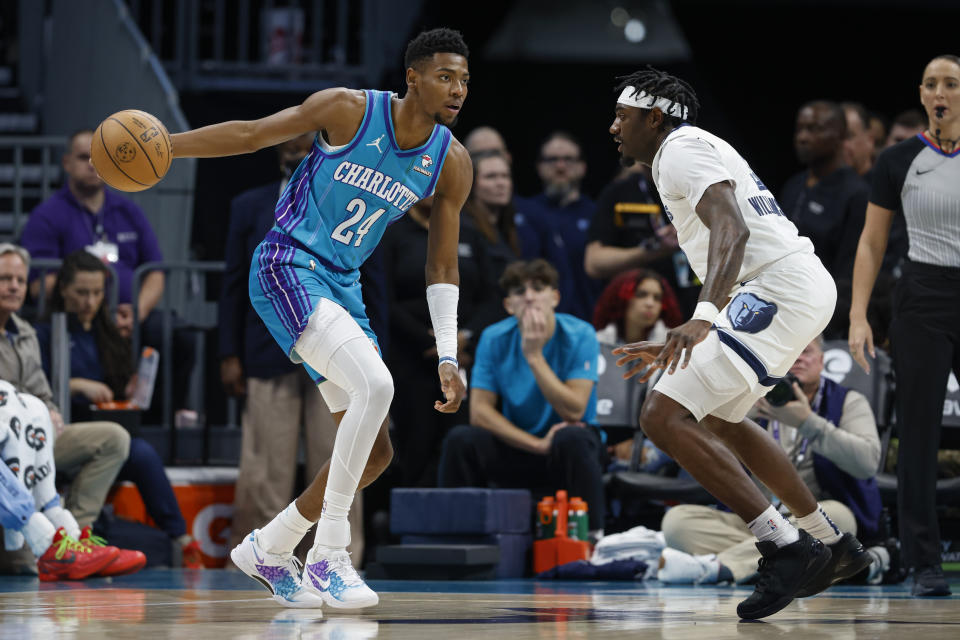 Charlotte Hornets forward Brandon Miller, left, looks to pass the ball against Memphis Grizzlies guard Vince Williams Jr. during the first half of an NBA basketball game in Charlotte, N.C., Saturday, Feb. 10, 2024. (AP Photo/Nell Redmond)