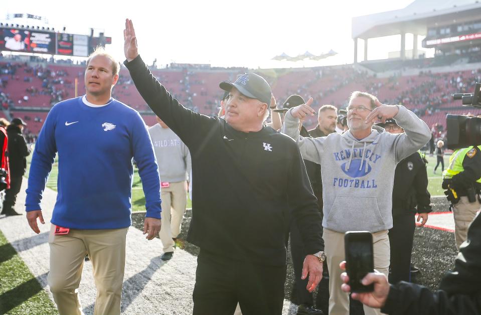 Kentucky Wildcats head coach Mark Stoops waves to the UK fans as special assistant Eddie Gran throws down Ls after the Wildcats beat Louisville 38-31 Saturday. Nov. 24, 2023