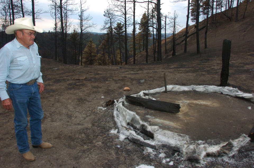 A July 20, 2012 photo shows Cecil Kolka examining the remains of a fiberglass water tank in the Custer National Forest that melted during the Ash Creek Fire near Volborg, Mont. Kolka's family lost an estimated 400 cows and calves to the 390-square-mile blaze.(AP Photos/Matthew Brown)