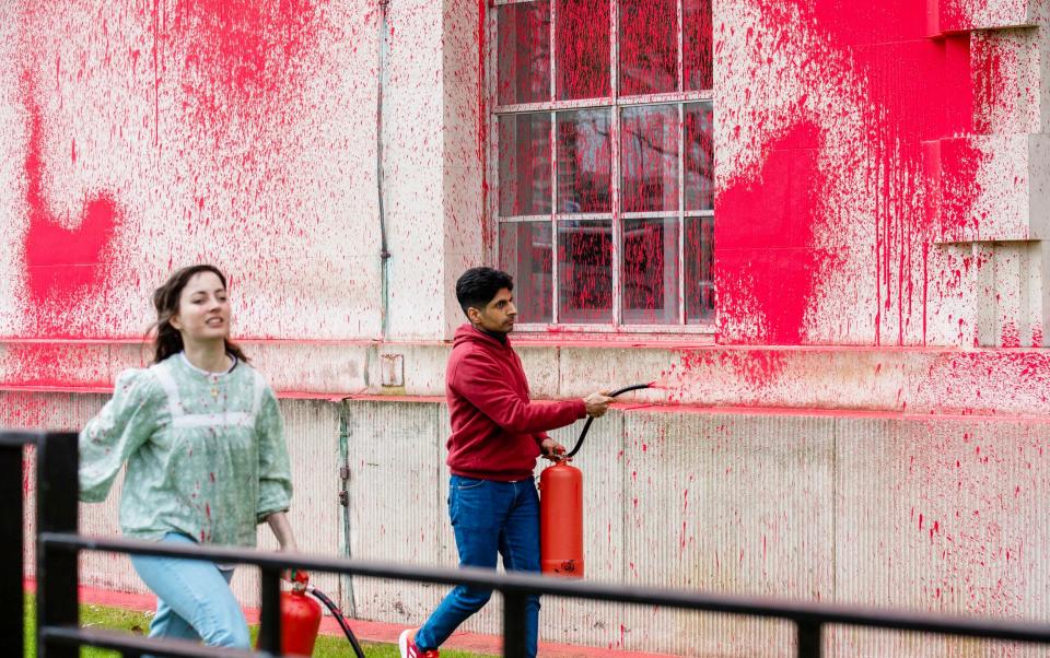 Several demonstrators spray red paint on to the Ministry of Defence building