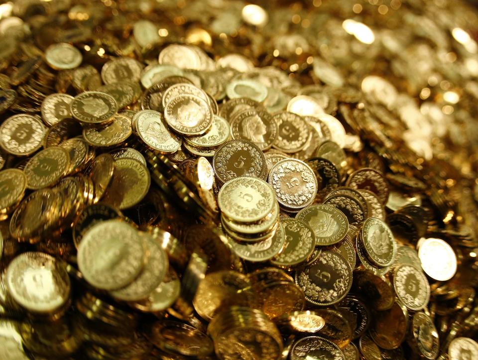 Swiss Francs five cent coins are heaped in a pile as members for the initiative "CHF 2,500 monthly for everyone" (grundeinkommen) open rolls of five cent coins in the old vault of the former Schweizerische Volksbank in Basel October 1, 2013. The committee dumped 8,000,000 five cent coins, weighting 15 tones, over the Federal Square in Bern on Friday, before delivering 126,000 signatures to the Chancellery to propose a change in the constitution to implement their initiative. The initiative aims to have a minimum monthly disposal household income of CHF 2,500 (US$ 2,700) given by the government to every citizen living in Switzerland. Picture taken October 1, 2013. REUTERS/Ruben Sprich (SWITZERLAND - Tags: POLITICS CIVIL UNREST)