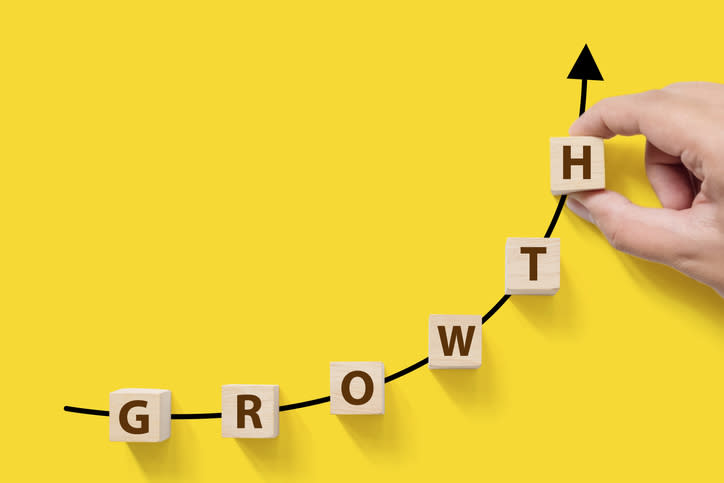 A hand placing blocks spelling the word growth onto an ascending chart.