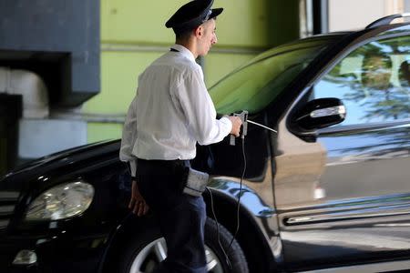 A security personnel, working for a private company, uses a detector as he checks a car entering a mall's parking lot in Beirut, Lebanon July 26, 2016. REUTERS/Jamal Saidi