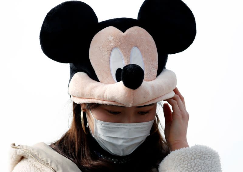 A visitor wearing protective face mask and Mickey Mouse costume, following an outbreak of the coronavirus, is seen outside Tokyo Disneyland in Urayasu